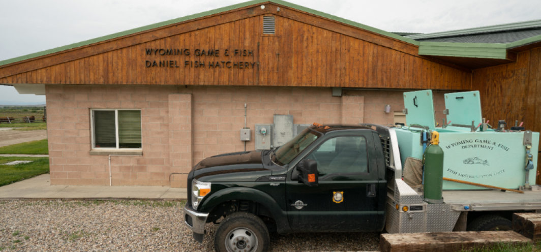 The side of the Wyoming Game and Fish Daniel Fish Hatchery with the fish distribution truck parked outside.